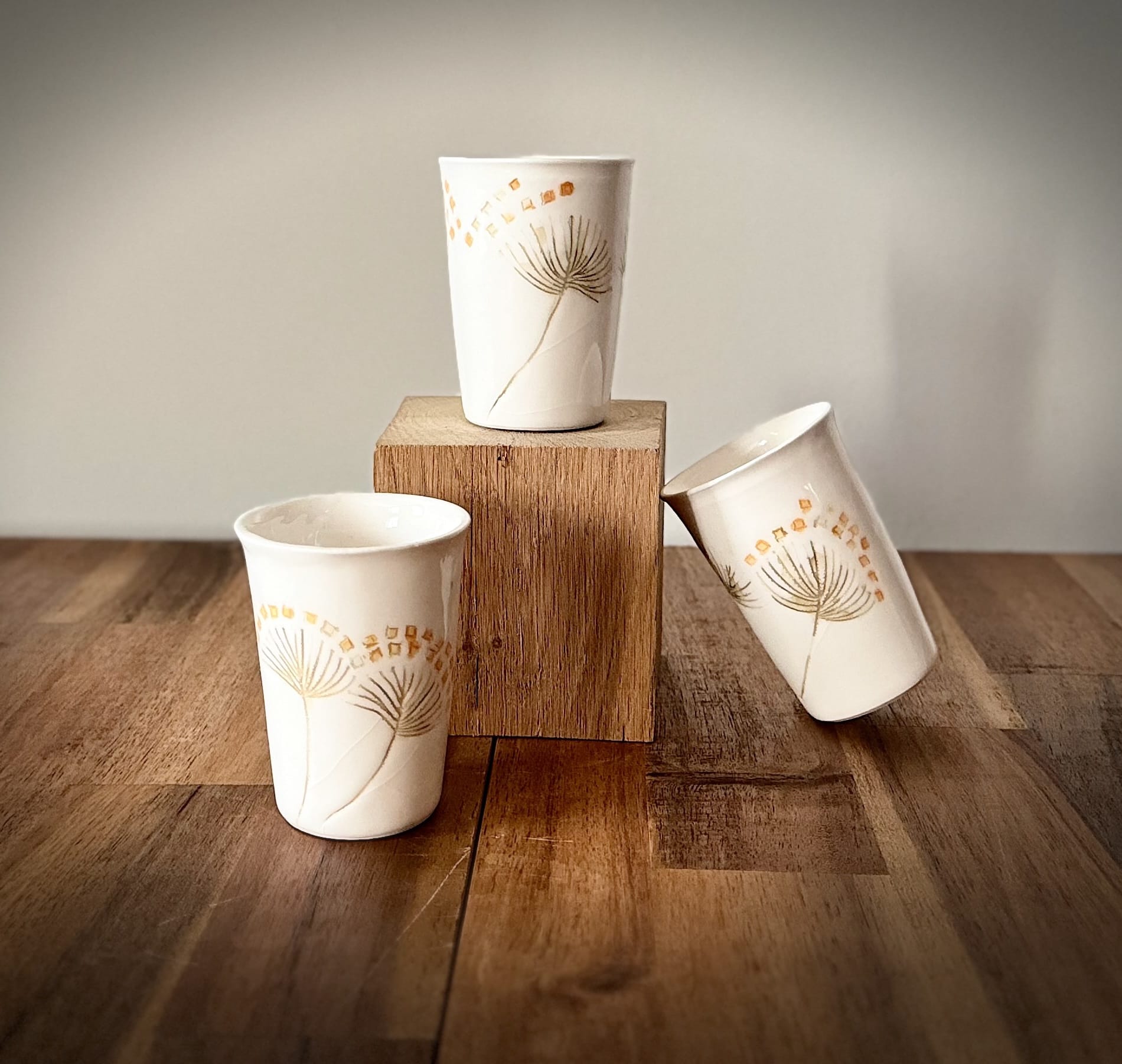 Trio de tasses blanches en porcelaine décorées de motifs rappelant une fleur de pissenlit